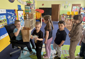 Dzieci ustawione w kolejce podchodzą do chłopca.