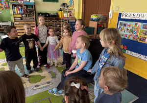 Dzieci ustawione w kole śpiewają "100 lat".