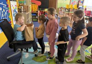 Dzieci ustawione w kolejce podchodzą do chłopca.