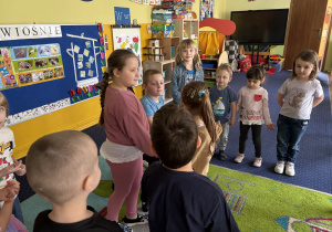 Dzieci ustawione w kole śpiewają "100 lat".