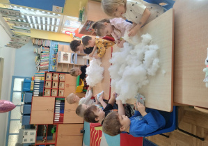 dzieci przy stolikach wykonują i ozdabiają króliki z materiału