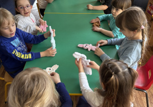 Dzieci siedzą przy stole ze swoimi zajączkami.