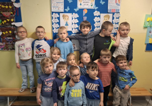 dzieci pozują do zdjęcia na tle tablicy poświęconej zagadnieniom spektrum autyzmu