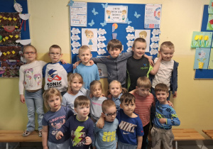 dzieci pozują do zdjęcia na tle tablicy poświęconej zagadnieniom spektrum autyzmu