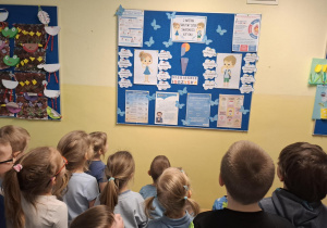 dzieci pozują do zdjęcia na tle tablicy poświęconej zagadnieniom spektrum autyzmu