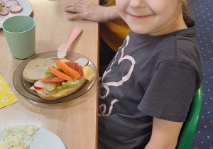 Dzieci siedzą przy stole i zjadają samodzielnie przygotowane śniadanie.