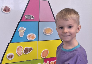 Chłopiec układa piramidę zdrowego żywienia.