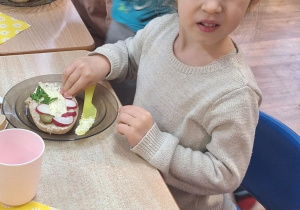 Dzieci siedzą przy stole i zjadają samodzielnie przygotowane śniadanie.