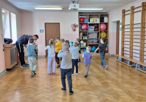 Dzieci stoją w rozsypce na sali gimnastycznej.