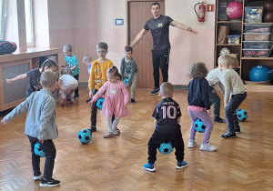 Dzieci wykonują ćwiczenia z piłką.