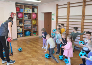 Dzieci wykonują ćwiczenia z piłką.