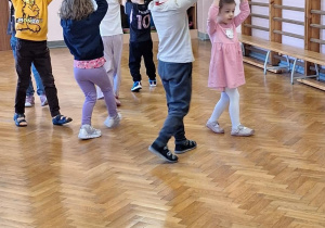 Dzieci wykonują ćwiczenia z piłką.