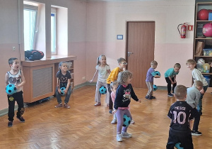 Dzieci wykonują ćwiczenia z piłką.