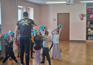 Dzieci wykonują ćwiczenia z piłką.