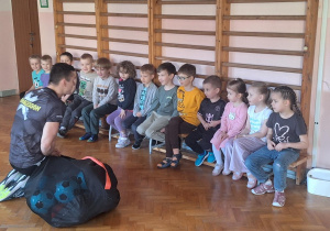 Dzieci siedzą na ławce i słuchają.