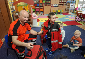 ratownik medyczny z wizytą u dzieci z grupy 2, dzieci poznają zawód ratownika medycznego, uczą się pierwszej pomocy