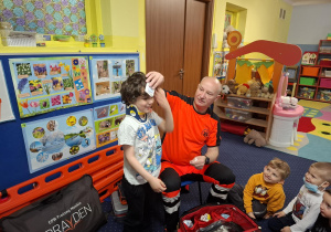 ratownik medyczny z wizytą u dzieci z grupy 2, dzieci poznają zawód ratownika medycznego, uczą się pierwszej pomocy