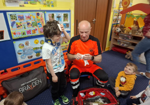 ratownik medyczny z wizytą u dzieci z grupy 2, dzieci poznają zawód ratownika medycznego, uczą się pierwszej pomocy