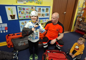 ratownik medyczny z wizytą u dzieci z grupy 2, dzieci poznają zawód ratownika medycznego, uczą się pierwszej pomocy