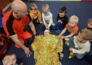 ratownik medyczny z wizytą u dzieci z grupy 2, dzieci poznają zawód ratownika medycznego, uczą się pierwszej pomocy