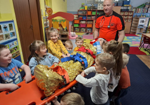 ratownik medyczny z wizytą u dzieci z grupy 2, dzieci poznają zawód ratownika medycznego, uczą się pierwszej pomocy