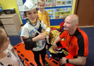 ratownik medyczny z wizytą u dzieci z grupy 2, dzieci poznają zawód ratownika medycznego, uczą się pierwszej pomocy