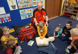 ratownik medyczny z wizytą u dzieci z grupy 2, dzieci poznają zawód ratownika medycznego, uczą się pierwszej pomocy