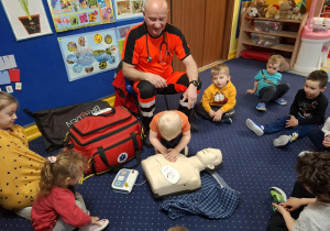 ratownik medyczny z wizytą u dzieci z grupy 2, dzieci poznają zawód ratownika medycznego, uczą się pierwszej pomocy