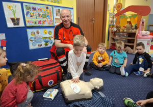ratownik medyczny z wizytą u dzieci z grupy 2, dzieci poznają zawód ratownika medycznego, uczą się pierwszej pomocy