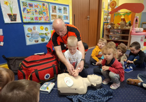 ratownik medyczny z wizytą u dzieci z grupy 2, dzieci poznają zawód ratownika medycznego, uczą się pierwszej pomocy