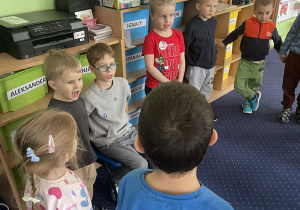 Dzieci ustawione w kole śpiewają "100 lat!".