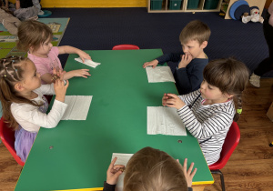 Dzieci siedzą przy stole i zjadają blok czekoladowy.