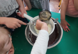 Dzieci zgromadzone przy stole wykonują blok czekoladowy.