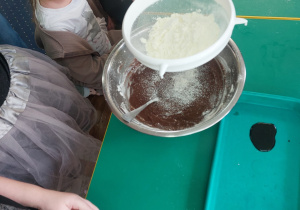 Dzieci zgromadzone przy stole wykonują blok czekoladowy.