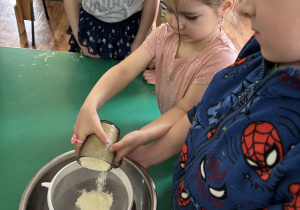 Dzieci zgromadzone przy stole wykonują blok czekoladowy.