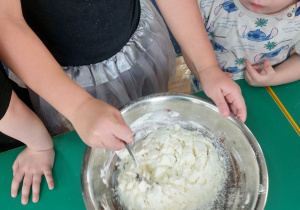 Dzieci zgromadzone przy stole wykonują blok czekoladowy.