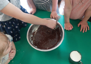 Dzieci zgromadzone przy stole wykonują blok czekoladowy.