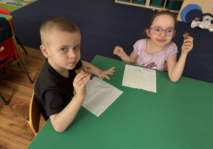 Dzieci siedzą przy stole i zjadają blok czekoladowy.