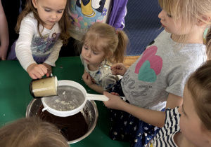 Dzieci zgromadzone przy stole wykonują blok czekoladowy.