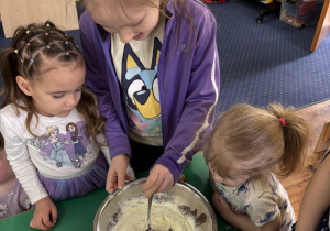 Dzieci zgromadzone przy stole wykonują blok czekoladowy.