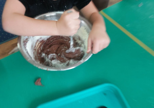 Dzieci zgromadzone przy stole wykonują blok czekoladowy.