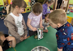 Dzieci zgromadzone przy stole wykonują blok czekoladowy.