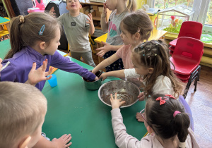 Dzieci zgromadzone przy stole smakują czekoladę.