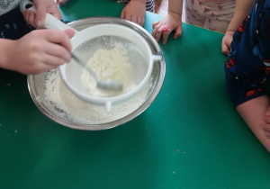 Dzieci zgromadzone przy stole wykonują blok czekoladowy.