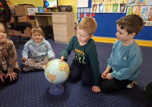 dzieci siedzą w kole oglądają globus