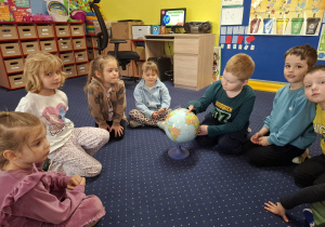dzieci siedzą w kole oglądają globus