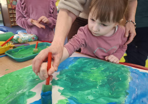 dziewczynka maluje plakat na dzień ziemi