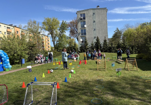 w ogródku przedszkolnym odbywają się sportowe konkurencje, w których uczestniczą dzieci