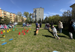 w ogródku przedszkolnym odbywają się sportowe konkurencje, w których uczestniczą dzieci