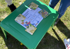 na małym, zielonym stoliku leży kartka, na której widać zebrane pieczątki za poszczególne konkurencje sportowe